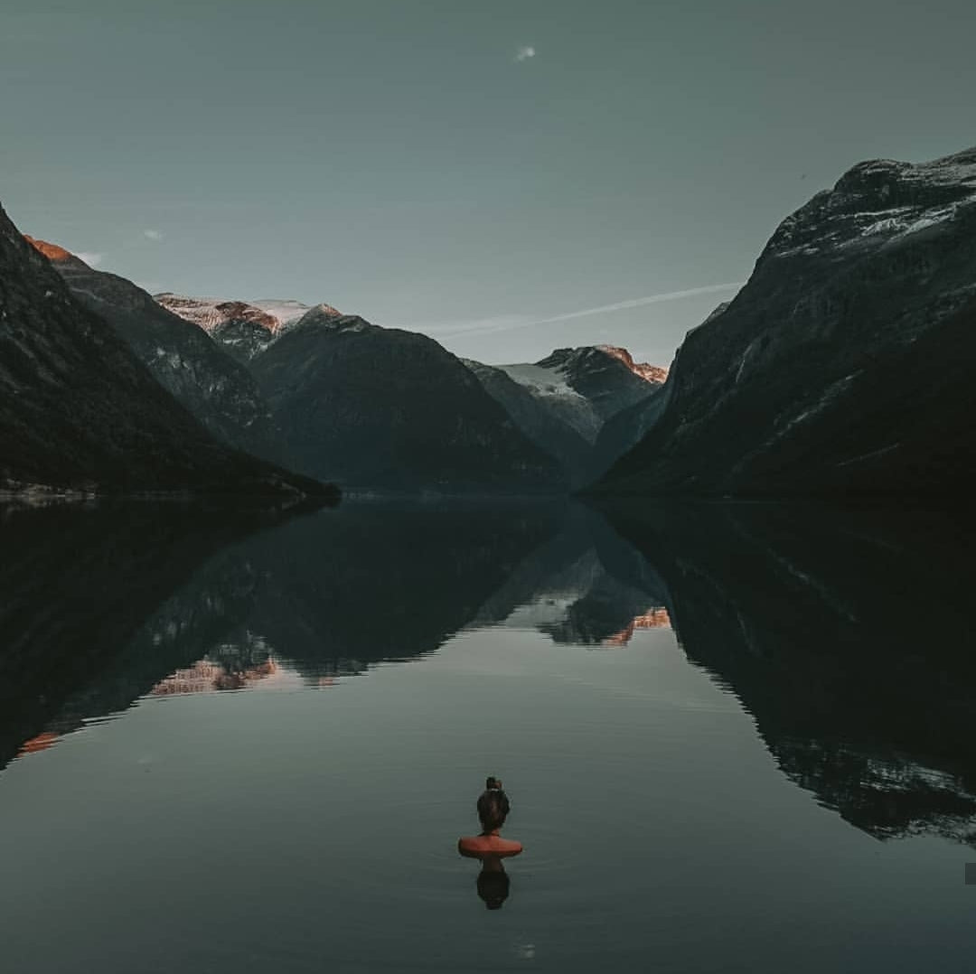 woman immersed in cold water looking at mountains